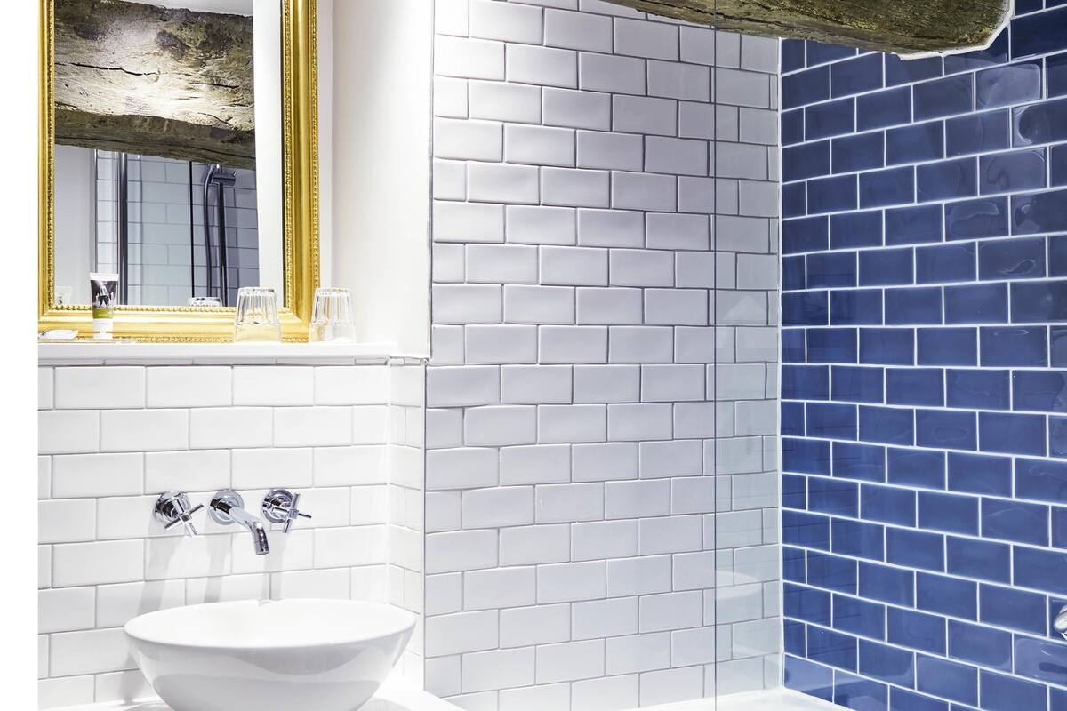 Une salle de bain avec un lavabo blanc, deux robinets et un miroir avec un cadre doré.