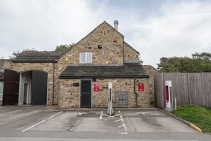 Een gebouw van steen met een zwarte deur, een garagepoort en een parkeerplaats met een paal.