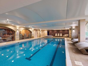 An indoor swimming pool with clear lane markings, a seating area with loungers, and a glass wall with a view. - Mercure Barnsley Tankersley (Barnsley)