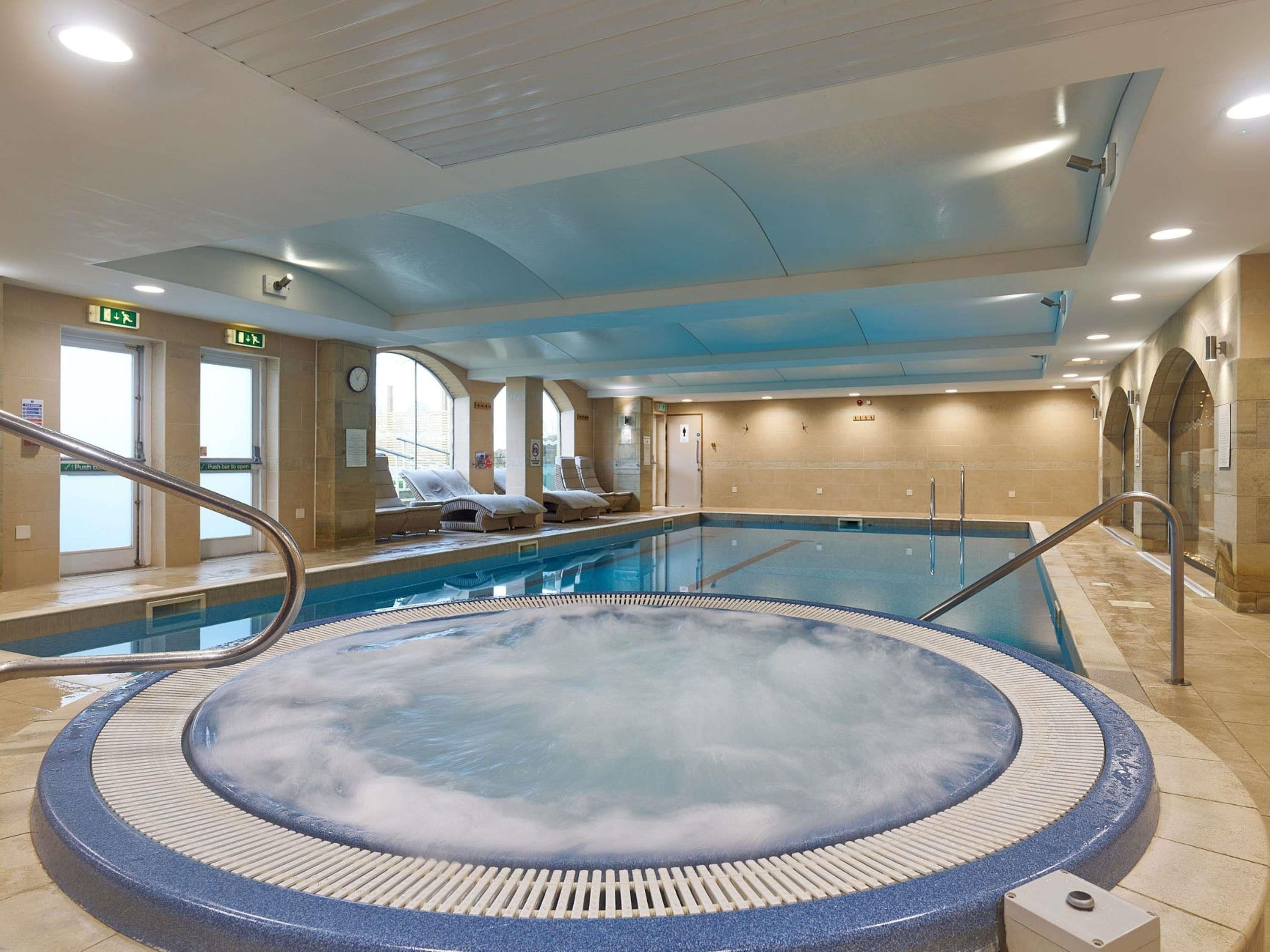 Una piscina interna con idromassaggio, poltrona a sdraio e tetto apribile.