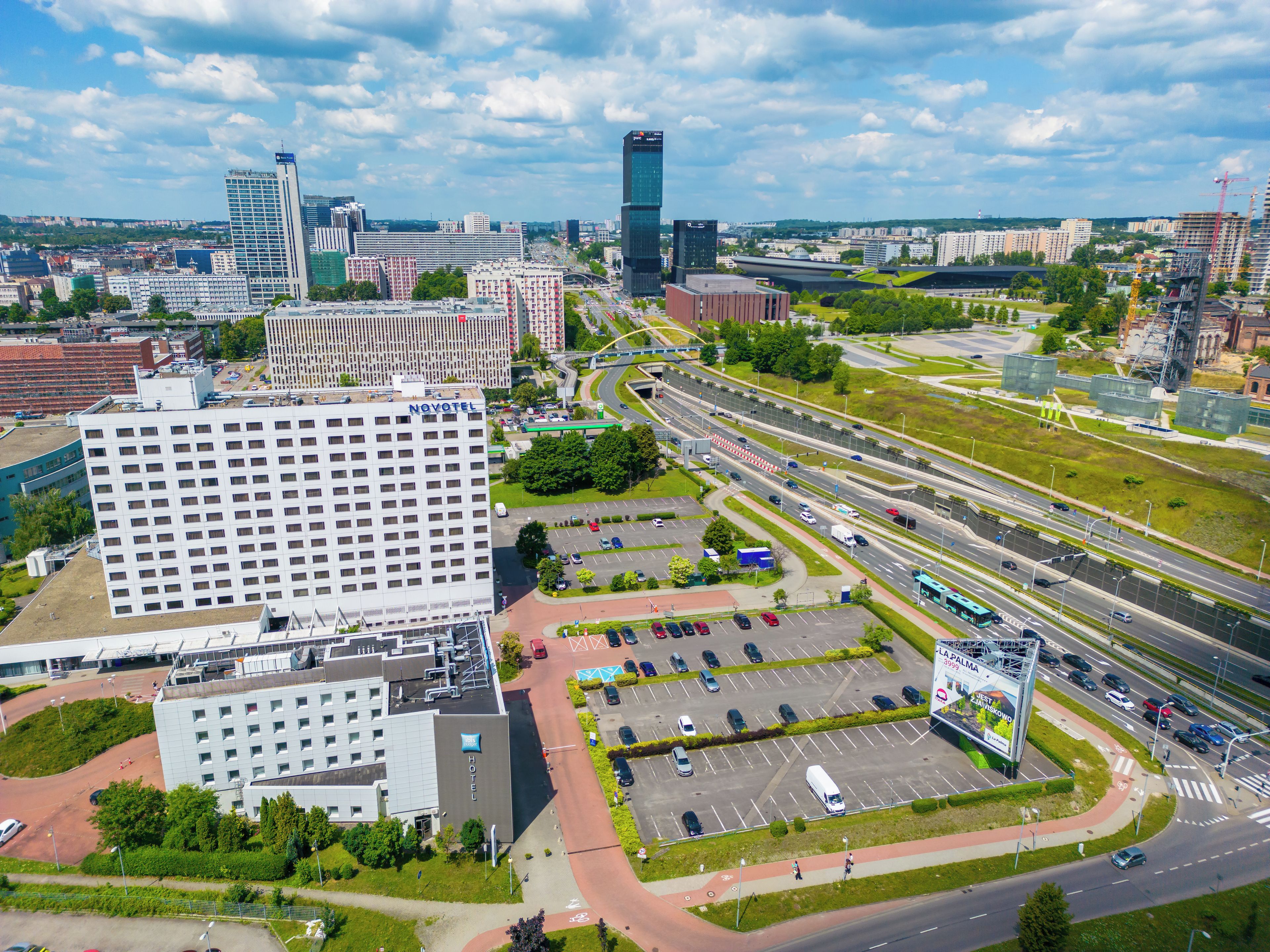 A modern hotel with a central courtyard, multiple parking levels, and a view of the surrounding urban area.