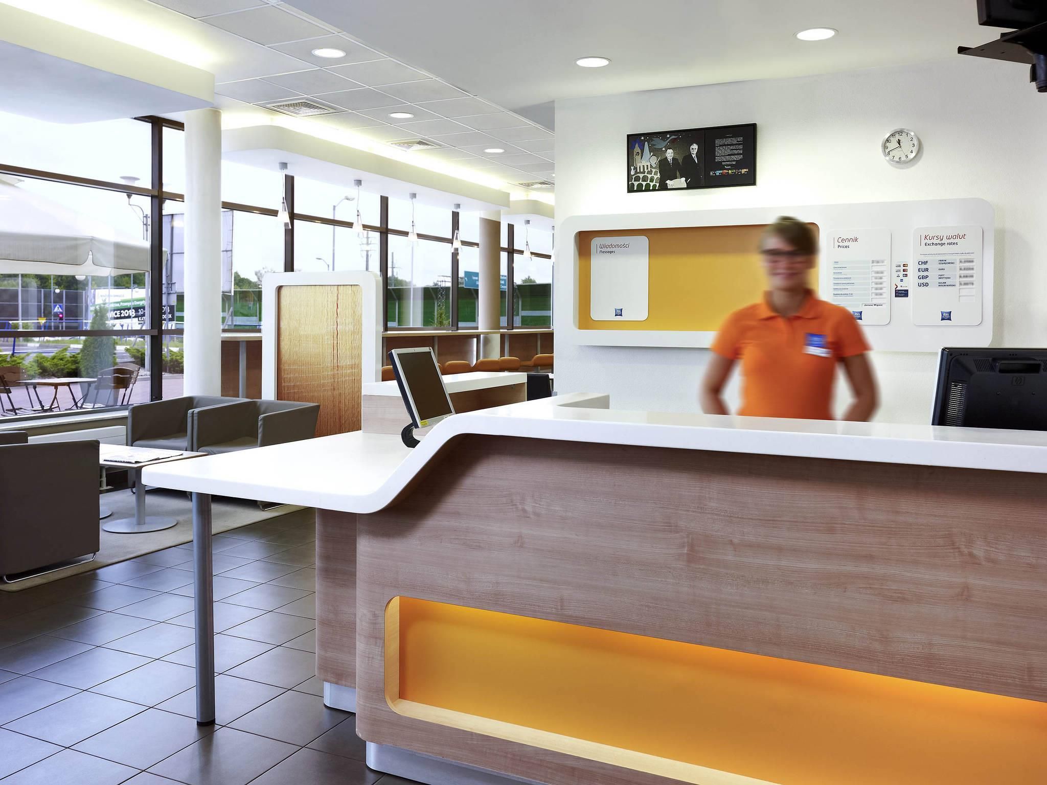 A modern reception desk with a digital screen, a clock, and informational posters.