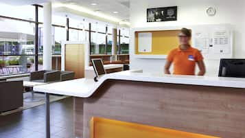 A modern reception desk with a digital screen, a clock, and informational posters.