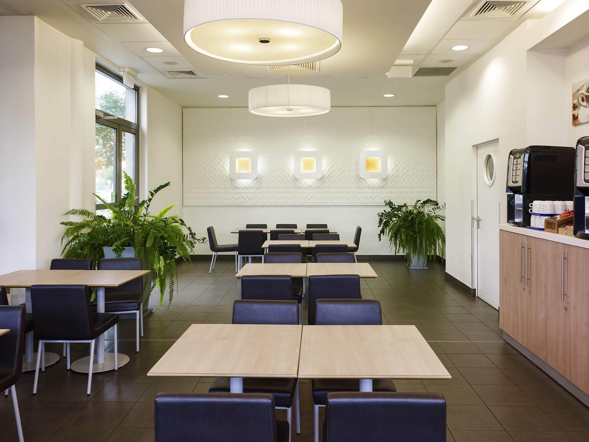 Un comedor moderno con mesas y sillas, una estación de café y paneles decorativos en la pared.