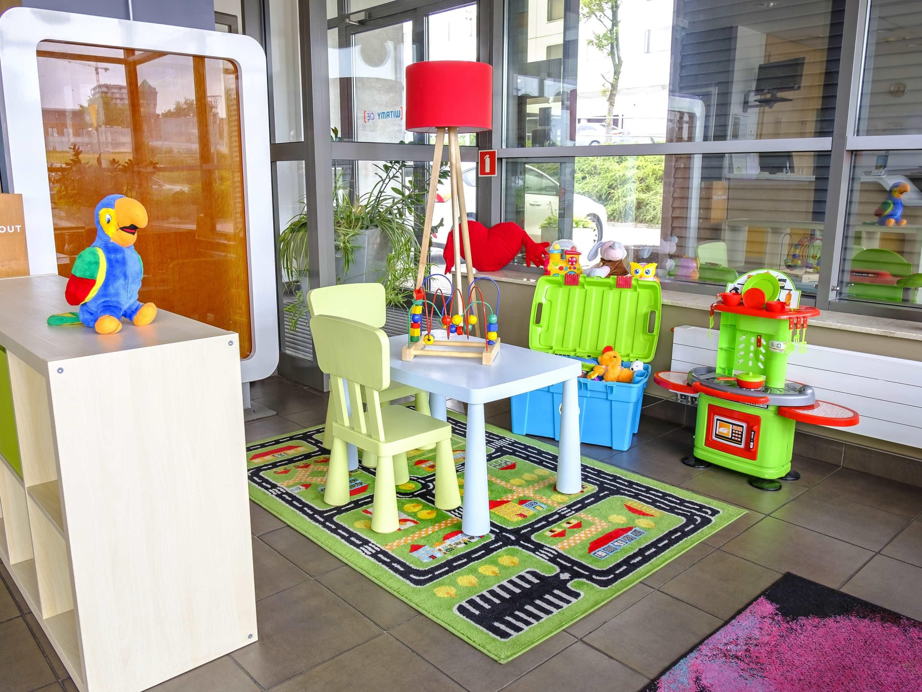 Un área de juegos infantiles con una mesa, sillas, juguetes y una alfombra colorida.