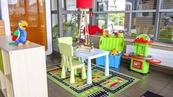 Un área de juegos infantiles con una mesa, sillas, juguetes y una alfombra colorida.