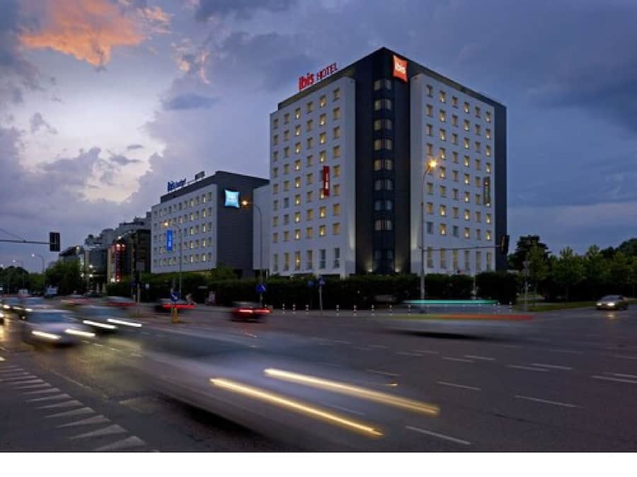 A hotel with multiple floors, a prominent sign, and a busy intersection with moving vehicles.
