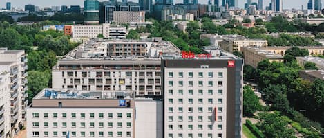 Un hotel moderno con techo plano, varios pisos y un patio central con un parterre floral.