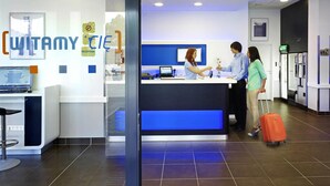 Una recepción con detalles azules, un cartel que dice 'WITAMY CIE' y un monitor de computadora.