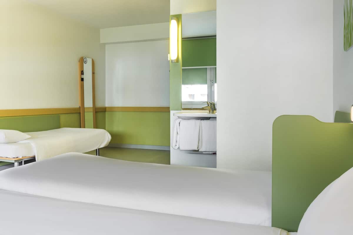 Ett hotellrum med två sängar, ett badrum och en spegel.