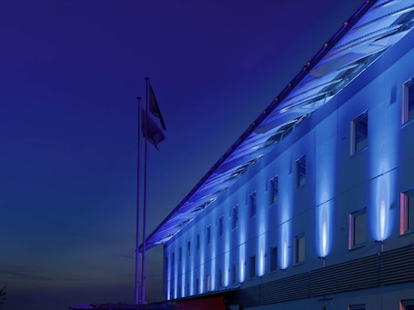 A building with a flagpole, large windows, and a flat roof.. ibis budget Warszawa West Station