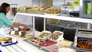 Montaje de bufé con diversas opciones de comida y una persona atendiendo.