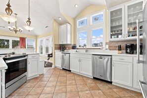 A spacious kitchen with white cabinetry, stainless steel appliances, and a large window providing natural light.