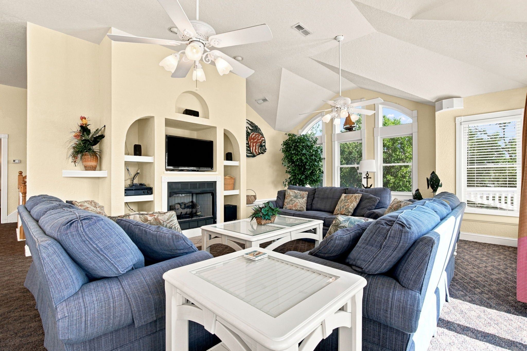 A living room with a fireplace, seating area, and ceiling fans.