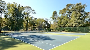 A tennis court with a net, surrounded by trees. - AMAZING HOME in Four Seasons in Duck! Private Pool! 10% OFF available summer weeks! (Duck)