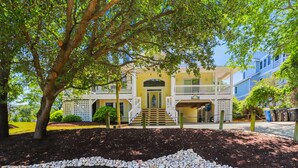 A two-story building with a central entrance, a staircase, and a covered porch area. - AMAZING HOME in Four Seasons in Duck! Private Pool! 10% OFF available summer weeks! (Duck)