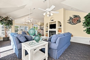 A living room with a blue sofa, a white coffee table, and a ceiling fan.