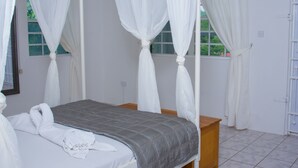 Une chambre à coucher avec un lit, une table de chevet et une fenêtre avec des rideaux.