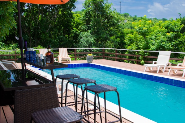 A swimming pool with lounge chairs and a bar area.