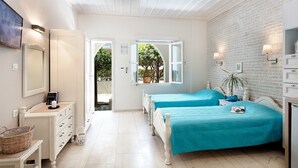 A bedroom with two beds, a white dresser, a mirror, and a brick wall. - Alkionides Seaside Apartments (Platanias)