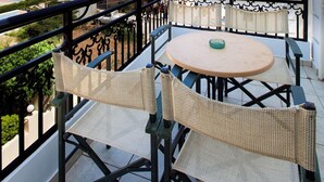 A balcony with a view of the sea, a table, and two wicker chairs. - Alkionides Seaside Apartments (Platanias)