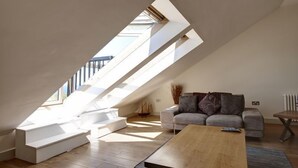 A modern loft with a sloped ceiling, built-in seating, a sofa, and a coffee table. - Stables 3 -  a llyn peninsula that sleeps 2 guests  in 1 bedroom (Pwllheli)