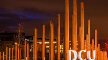 A night view of a building with the letters "DCU" illuminated on the ground.