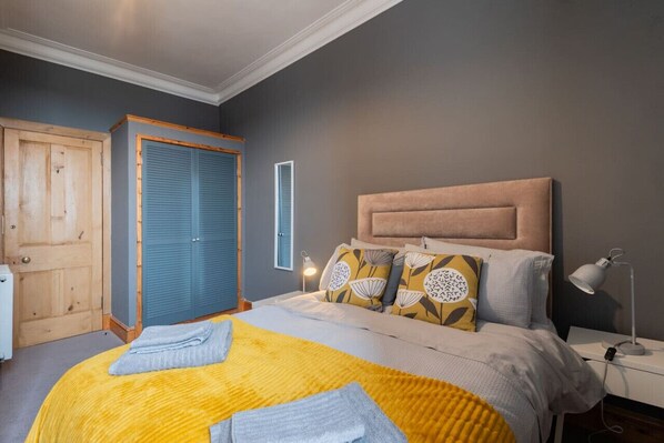 A bedroom with a bed, bedside table, lamp, and wardrobe.