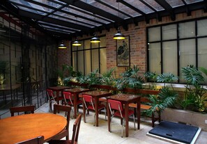 Un comedor interior con paredes de ladrillo, ventanas amplias y lámparas colgantes.