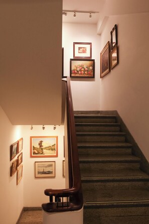 A staircase with a handrail, flanked by walls adorned with framed artworks.