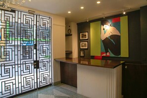 Zona de recepción con una reja metálica decorativa, un mostrador y una pared con cuadros enmarcados.