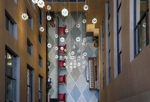 A corridor with multiple floors, featuring a series of red chairs and a piano.