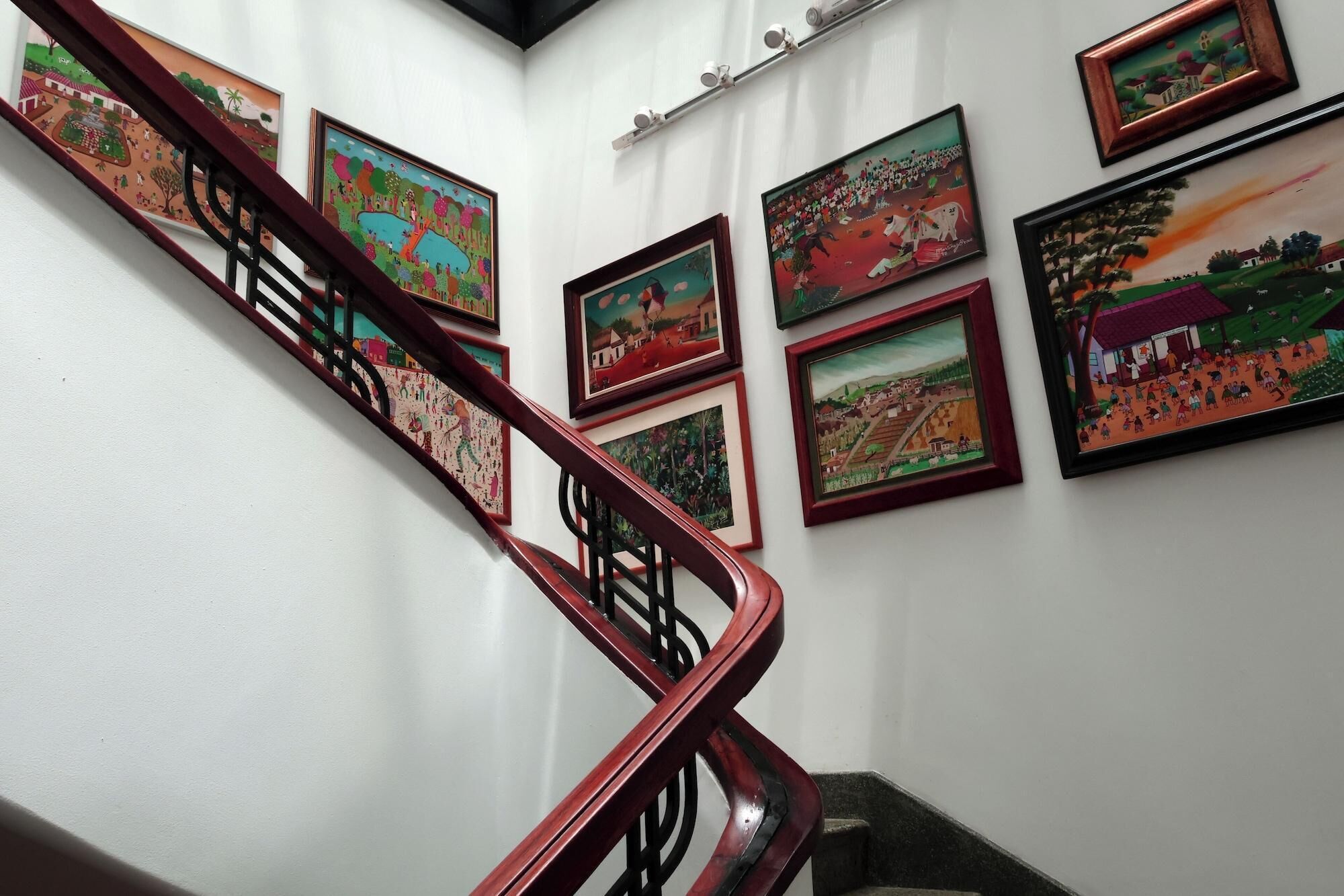 A staircase with handrails and multiple framed artworks on the walls.