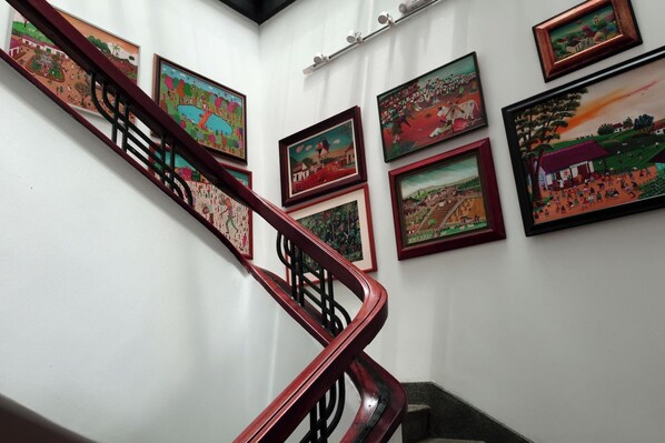 A staircase with handrails and multiple framed artworks on the walls.