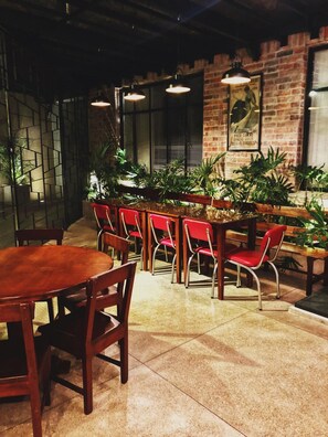 A restaurant interior with brick walls, hanging pendant lights, and red chairs. - Hotel Museo San Moritz (Bogotá)