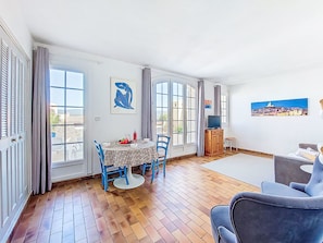 Et værelse med spisebord, stole, sofa, fjernsyn og kunst på væggene.