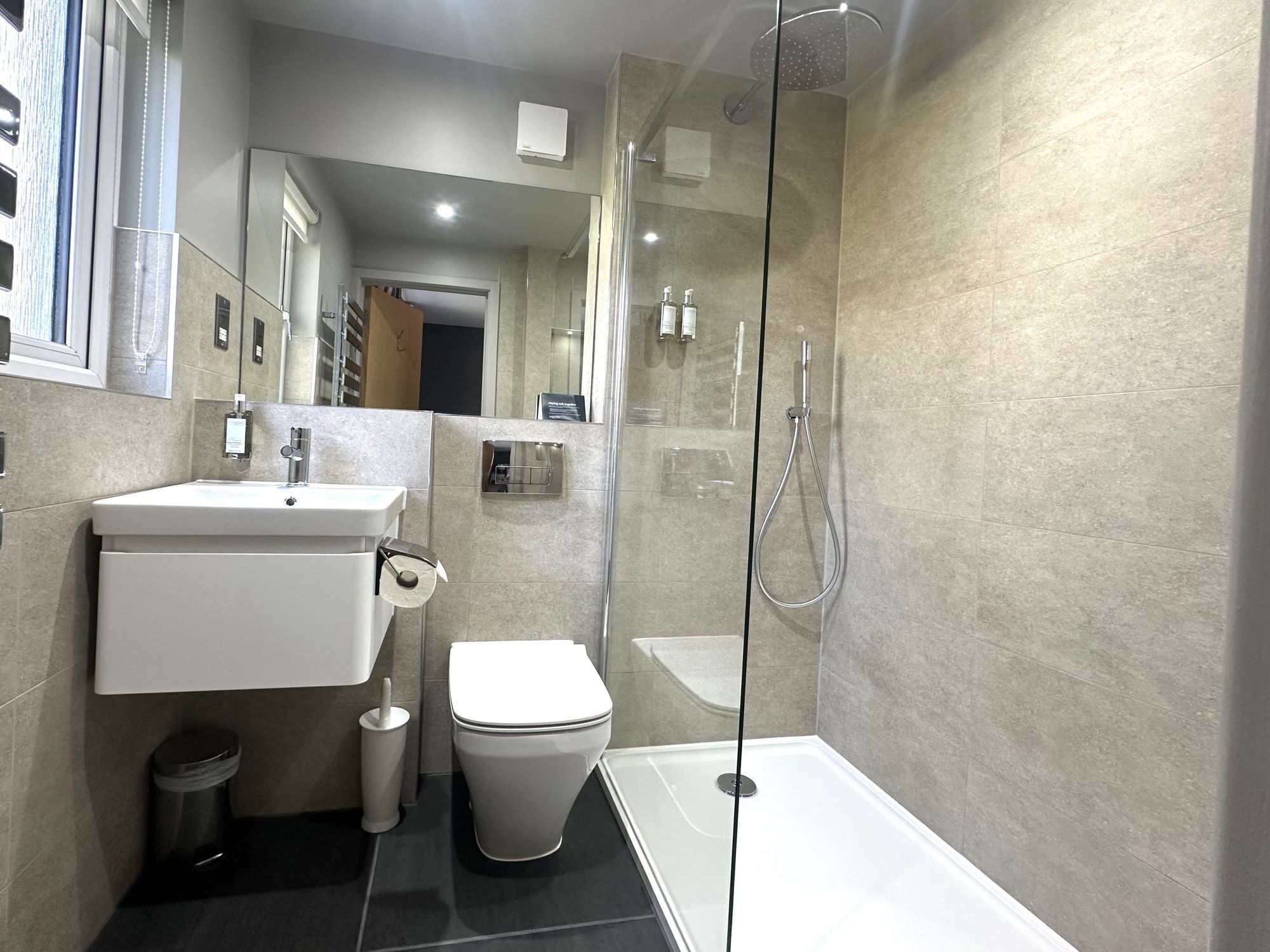 Une salle de bain moderne avec une douche à parois de verre, un lavabo blanc et des toilettes.
