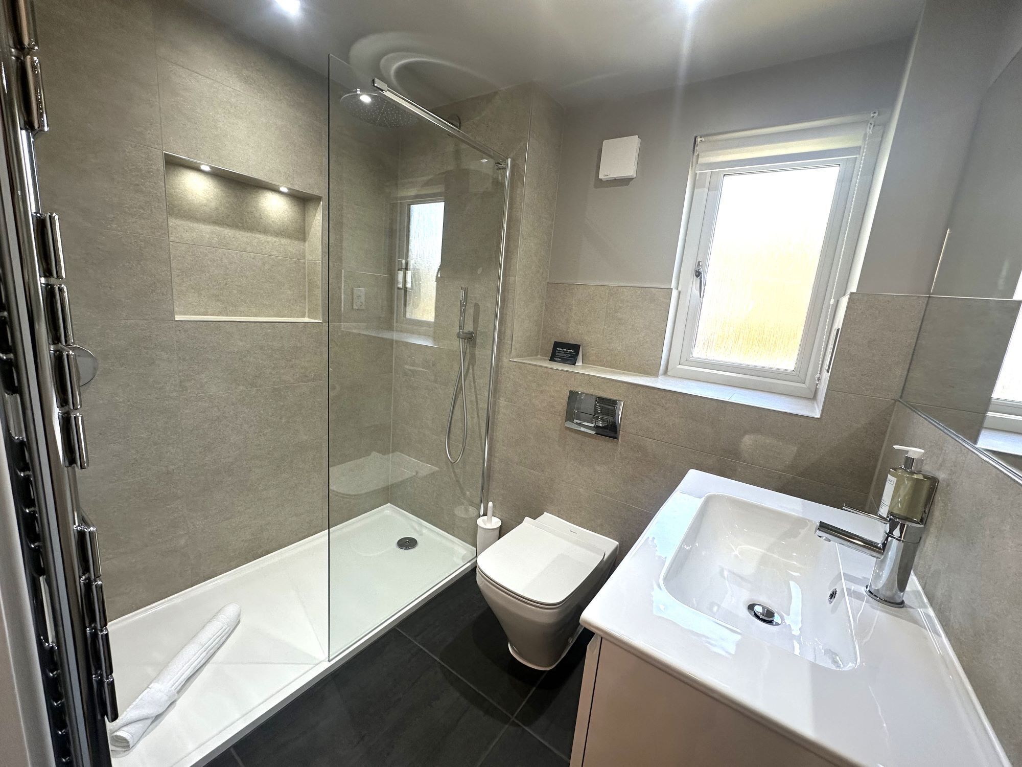 A modern bathroom with a glass-enclosed shower, a white sink, and a toilet.