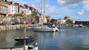 Un puerto con barcos amarrados, un muro de piedra y edificios a lo largo del muelle.