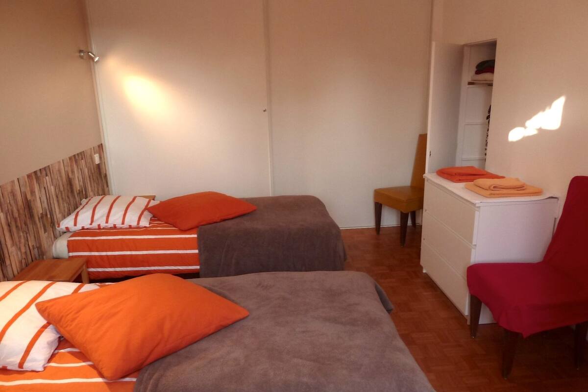 A room with two beds, a chair, a desk, and a wardrobe.