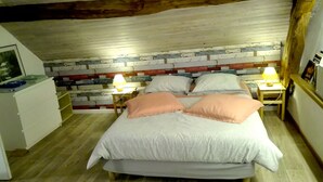 Ein Schlafzimmer mit einem Bett, zwei Nachttischen mit Lampen, einem Holzkopfende, einer weißen Kommode und Holzboden.