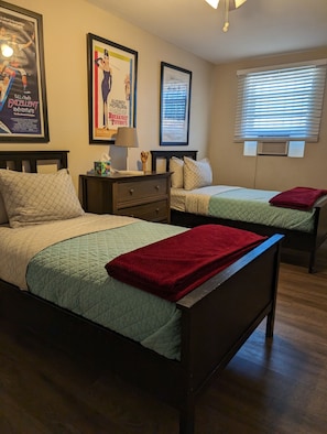 A hotel room with two beds, a nightstand, a lamp, and framed posters on the wall. - Stylish Desert Oasis in Tempe (Tempe)