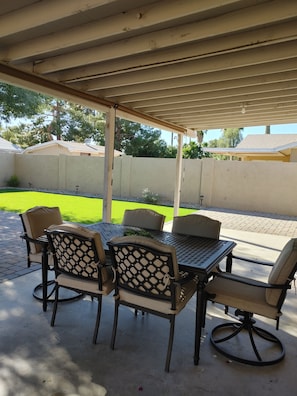 An outdoor patio with a covered seating area, a table, and chairs. - Stylish Desert Oasis in Tempe (Tempe)