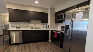 Una cocina moderna con armarios oscuros, electrodomésticos de acero inoxidable y suelo de madera.