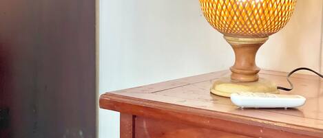 A wooden table with a lamp and a remote control on it.