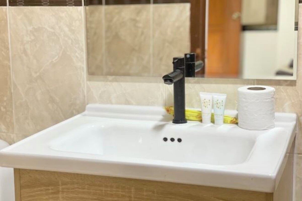 A bathroom with a white sink, a black faucet, and a mirror above it.