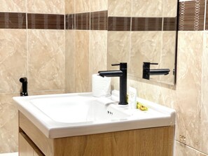 A bathroom sink with a white countertop, a black faucet, and a mirror above it. - SKY Residence - 50m to Museum and Riverside (Phnom Penh)