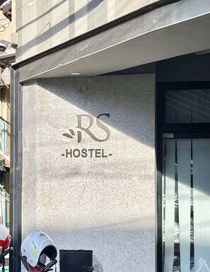 A hostel with a sign reading "RS HOSTEL" on a textured wall. - SKY Residence - 50m to Museum and Riverside (Phnom Penh)