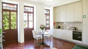 Une cuisine moderne avec des meubles blancs, une table à manger avec des chaises et un lustre.
