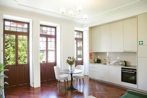A modern kitchen with white cabinets, a dining table with chairs, and a chandelier.